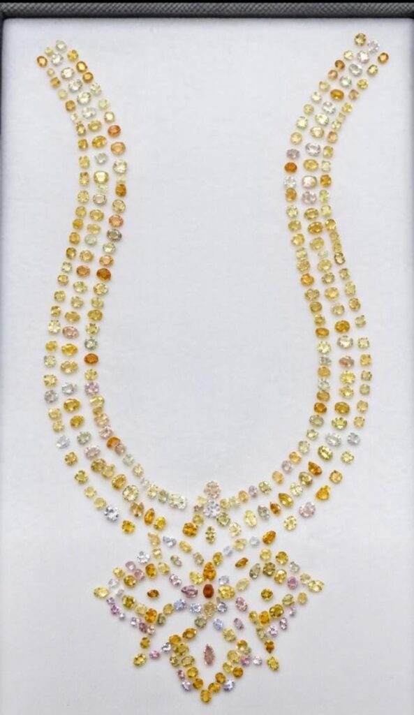 A stunning necklace design featuring clusters of natural fancy yellow diamonds in various cuts and sizes, arranged in an elegant U-shaped collar with a intricate floral-inspired pendant motif, set against a clean white background for maximum sparkle.